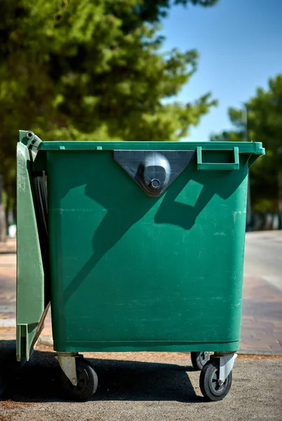 detail of an empty green garbage container on the street