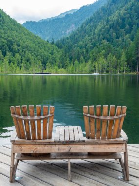 Plajda iki boş tahta sandalye, dağ gölünün güzel manzarası, dağlarda tatil, lüks yaz tatili konsepti.