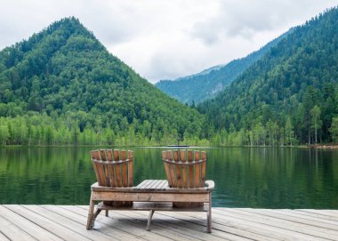 Plajda iki boş tahta sandalye, dağ gölünün güzel manzarası, dağlarda tatil, lüks yaz tatili konsepti.