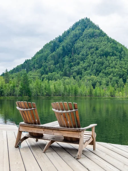 Two empty wooden deck chairs on the beach, beautiful landscape of mountain lake, vacation in the mountains, luxury summer vacation concept