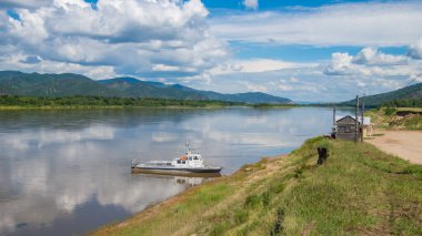 Nehrin kırsal kesiminde yaz manzarası. Sakin bir nehir kıyıya demir atmış eski bir tekne..