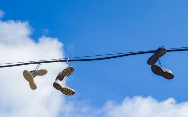 Spor ayakkabıları mavi gökyüzüne karşı kablolara tutunur..