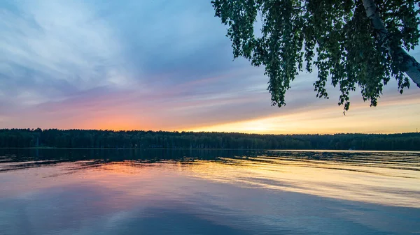 Sakin bir nehrin üzerinde yaz günbatımı manzarası.