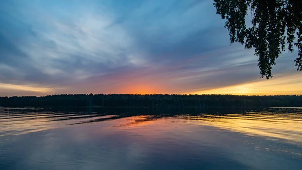 Sakin bir nehrin üzerinde yaz günbatımı manzarası.