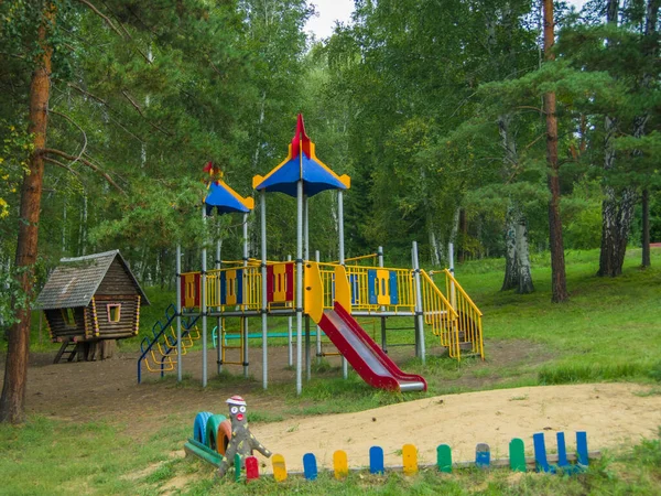 Parktaki oyun parkı ağaçların arasında.