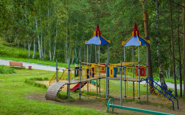 Parktaki oyun parkı ağaçların arasında.