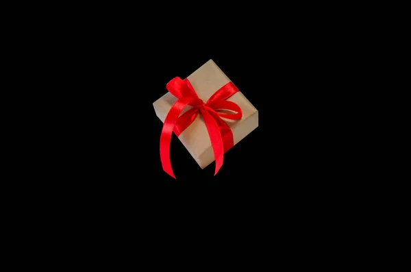 Kırmızı kurdeleli hediye kutusu, siyah arkaplanda izole edilmiş kopyalama alanı. Satış konseptleri, indirimli fiyatlar, Kara Cuma, Noel hediyeleri ve alışveriş, Noel için tebrik kartı, sevgililer günü veya yeni yıl