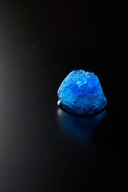 Solunda ışık olan bir mat yüzeyindeki güzel mavi buz parçasının dikey fotoğrafı.