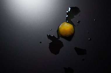 Mat yüzeyinde su sıçramaları ve arka plan ışık manzaralı güzel sarı bir buz parçası.