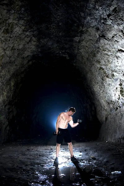 Varón Joven Fuerte Levantando Pesas Una Cueva — Foto de Stock