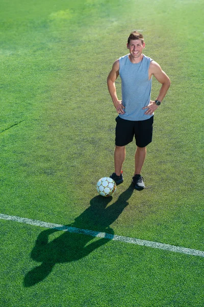彼のボールを保持している笑みを浮かべてグリーン フィールドに立って選手 — ストック写真