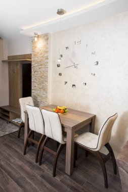 Tablonun üst kısmındaki büyük bir saat ile modern yemek odası