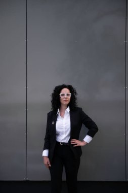 Kendine güveni tam genç bir iş kadını modern gri arka planda kameraya bakıyor.