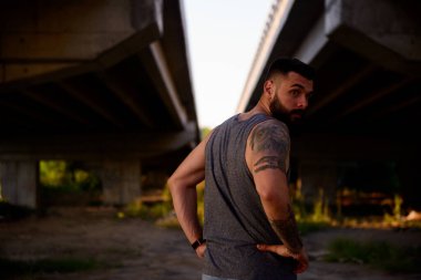 Koronavirüs salgınından dolayı içeride kalabalıktan kaçınmak için dışarıda egzersiz yapan sakallı genç bir adam.