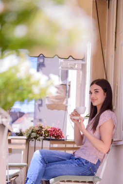 Genç kız güzel bir balkonda kahvesinin tadını çıkarıyor.