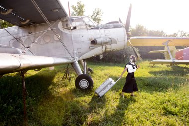 Siyah etekli genç bir kadın eski bir havaalanında bagajını çekiyor.