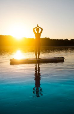 Gün doğarken meditasyon yapan ve yoga yapan bir kadın.