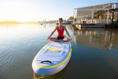 Gün doğarken meditasyon yapan ve yoga yapan bir kadın.