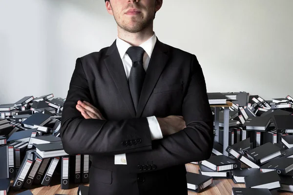 Businessman crossed arms in front of a large pile of ring binder — Stock Photo, Image