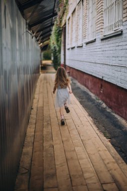 Little girl running away between buildings
