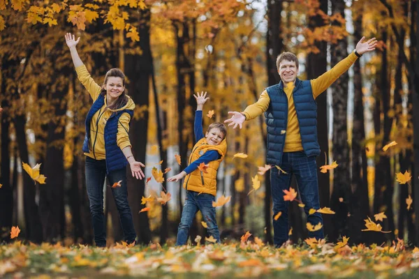 Una familia feliz lanzando hojas de otoño y mirando a la cámara —  Fotos de Stock