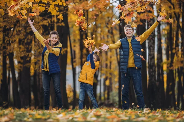 Una familia feliz tirando hojas de otoño sobre sus cabezas —  Fotos de Stock