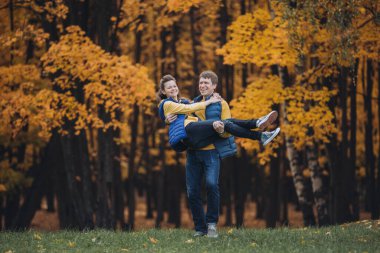 Mutlu bir çift sonbahar parkında eğleniyor.