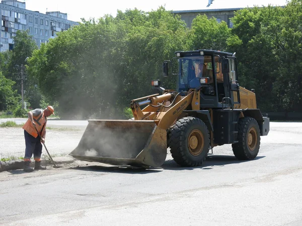 Omsk, Rusya - 08 Haziran 2020: Kamu hizmetleri asfalt yolu temizliyor