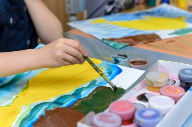 Çocuk elinde fırça tutuyor ve çok renkli çizimler çiziyor beyaz kağıt ve guaj ile. Çocukların yaratıcılığı kavramı.