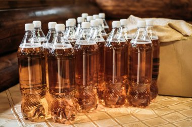 Açık köpük biralı şeffaf plastik şişeler, mantarlarla kapatılmış, masanın üzerinde duruyor..