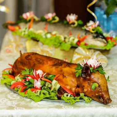 Genç domuz taze sebze ve otlarla süslenmiş bir tabağın üzerinde güzelce yatıyor..