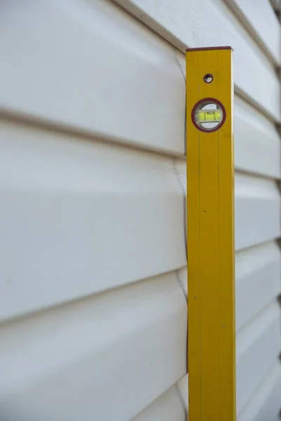 The building level tool measures the level surface of a building wall. Control of ongoing construction work. Vertical photo, selective focus, shallow depth of field