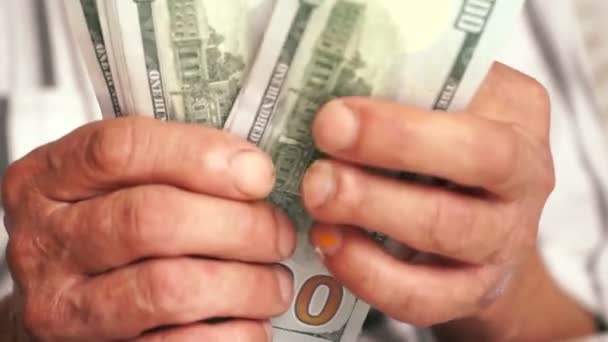 Close-up of an elderly mans hands holding American dollar bills.A pensioner is counting money, holding them in his hands.Home budget and savings. Selective focus
