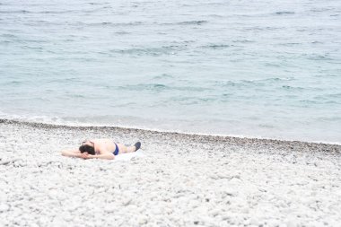 Çakıl taşlı plajda dinlenen insanlara bakın.