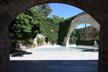 Sarmaşık duvarlı ve kemerli kaledeki yapay gölet manzarası