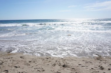 Güneşli bir günde kumsaldaki dalgaları izle