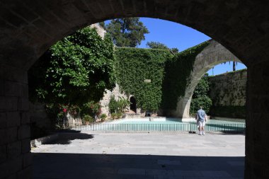 Sarmaşık duvarlı ve kemerli kaledeki yapay gölet manzarası