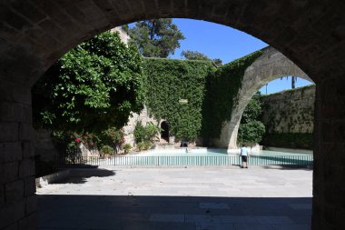 Sarmaşık duvarlı ve kemerli kaledeki yapay gölet manzarası