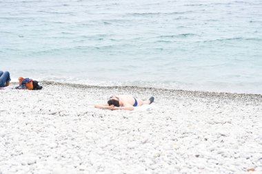 Çakıl taşlı plajda dinlenen insanlara bakın.