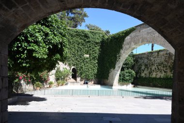 Sarmaşık duvarlı ve kemerli kaledeki yapay gölet manzarası