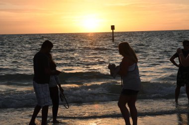 Sahildeki insanların siluetlerinin güzel bir manzarası.