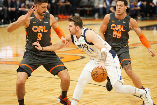 Dallas Mavericks player Luka Doncic #77  tries to run pass Orlando Magic Players Nikola Vucevic #9 and Aaron Gordon #00 during the game at the Amway Center in Orlando Florida on Friday February 21, 2020.  