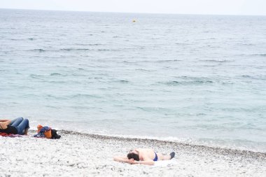 Çakıl taşlı plajda dinlenen insanlara bakın.