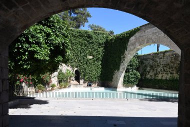 Sarmaşık duvarlı ve kemerli kaledeki yapay gölet manzarası