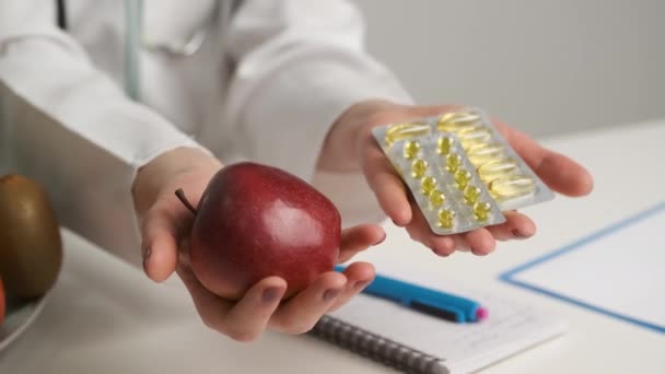 Docteur en manteau blanc tient une pomme et des oméga 3. Alimentation et santé — Video