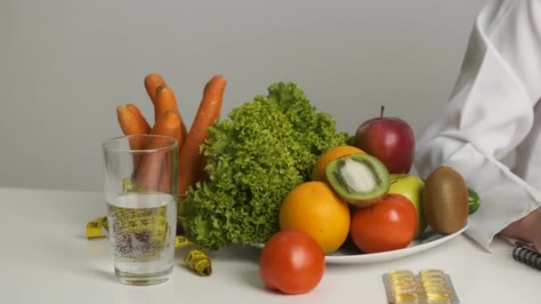 Nutricionista doctora en un vestido médico se sienta en el trabajo y prescribe una dieta saludable — Vídeos de Stock