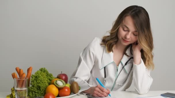 Femme médecin nutritionniste en robe médicale se trouve au travail et prescrit une alimentation saine — Video