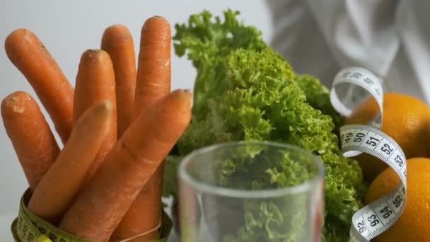 Gemüse und Obst auf dem Tisch für eine gesunde Ernährung. Ernährung. Salat, Karotten, ein Glas Wasser, Kiwi, Tomate, Orange und Maßband — Stockvideo