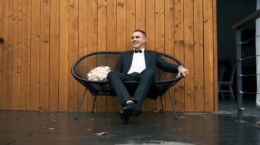 Aşık genç bir adam terasta bir buketle köşkünde boğuşuyor.
