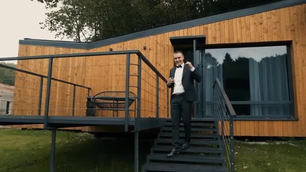 Exitoso feliz sonriente hombre de negocios sale de su elegante casa y bebe coñac después de una reunión apresurada de negocios — Vídeos de Stock